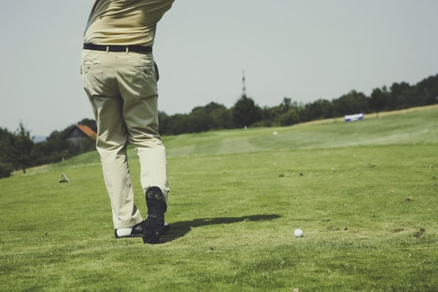 Golfer mid-swing on grassy golf course