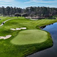 Aerial golf course green with bunkers and pond